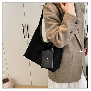 Close-up of black suede tote bag featuring a matching mini card pouch on shoulder strap