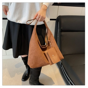 Detail of brown suede tote bag with matching leather pouch charm and metal hardware