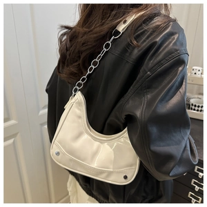 Detail of white glossy crescent bag with silver chain strap on a black leather jacket