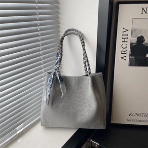 Large gray leopard print tote bag with woven handles and decorative scarf on a window sill
