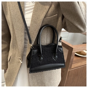 Detail view of plush black faux fur handbag with sleek leather trim and gold hardware