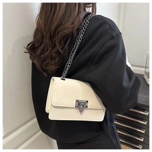 Detail of a creamy beige chain bag with dark grey metal buckle and sleek PU leather texture