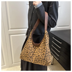 Detail of large leopard print tote bag with brown leather strap worn by a model