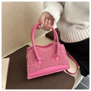 Detail view of rose red faux fur handbag with smooth leather trim and dual handles