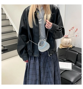Modelo con chaqueta de cuero elegante y bolso de mano metálico plateado con cadena