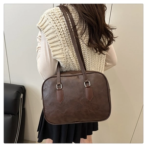 Dark brown retro PU leather Boston bag shown on shoulder in a minimalist setting