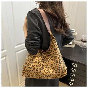 Detailed view of leopard print suede hobo bag worn by a model in a minimalist home setting