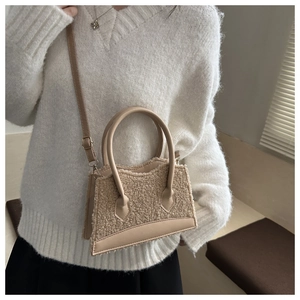 Close-up of beige fleece crossbody bag showing fluffy texture and leather handles