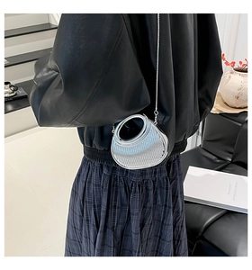 Detail of silver crescent acrylic bag with textured surface and sleek metal chain strap