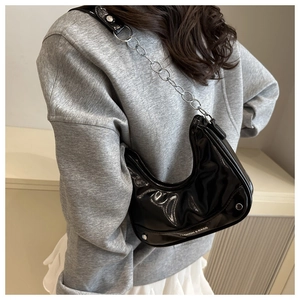 Detail of black patent leather half-moon bag with silver chain and FASHION & BAGS print