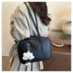 Detail of a large black matte leather tote bag featuring a cute white cloud pendant
