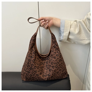 Close-up of leopard print hobo bag featuring brown leather strap and textured fabric