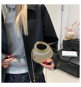 Detalle de bolso de fiesta dorado plisado con asa redonda y correa de cadena