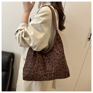 Side view of leopard print tote bag with brown leather strap worn by a model