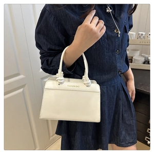 Detailed view of white minimalist handbag with knot handle and Fashion Bag print