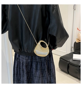 Detail of metallic mini bag with radial texture and circular handle on model back