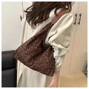 Close-up of brown leopard print tote bag with wide shoulder strap on model side view