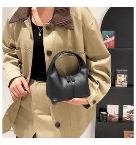 Detailed view of the smooth matte black leather texture and metal zipper of the handbag