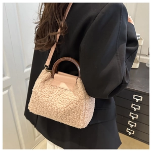 Detail of beige fleece handbag with round brown handle and leather strap on model