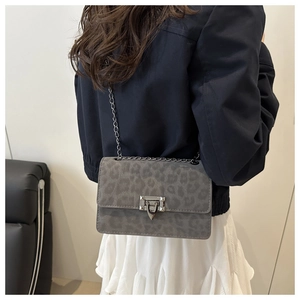 Detail of grey leopard print crossbody bag with metallic chain strap worn by a model