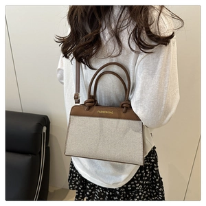 Detail of vintage canvas and brown leather handbag showing gold lettering and strap texture
