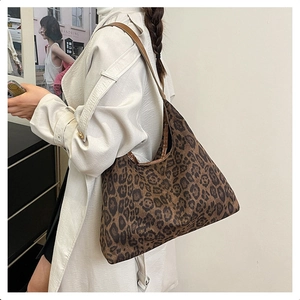 Spacious leopard print tote bag with brown shoulder strap worn on a white trench coat