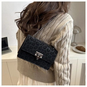 Detail of a black leopard print crossbody bag with chain strap on a cozy sweater