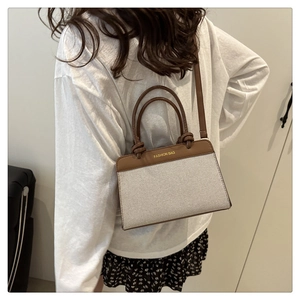 Close-up of beige canvas patchwork bag with brown leather handles and printed text