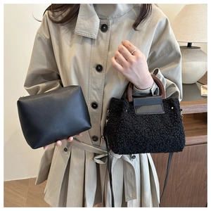 Detail of black teddy fleece handbag with wooden handle and matching leather clutch bag