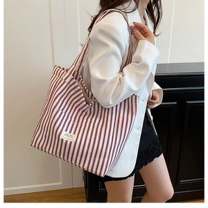 Detail shot of a large red and white striped canvas tote bag worn over the shoulder
