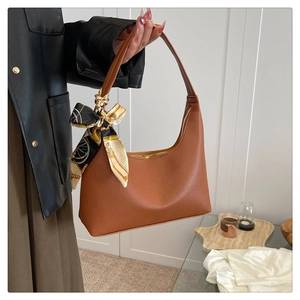 Detail of brown lychee-patterned hobo bag with an elegant decorative silk scarf on handle