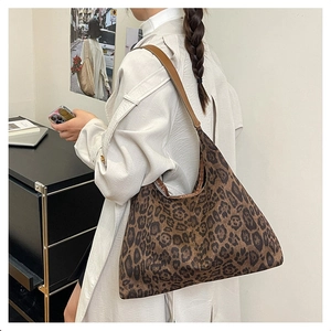 Fashionable large leopard print tote bag with brown leather straps in a street style view