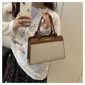 Close-up of beige woven canvas handbag with brown leather trim and knot handle