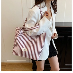 Detail of red and white striped canvas tote bag with woven label and shoulder straps