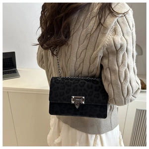 Close-up of leopard print shoulder bag with silver chain and metal lock on a model