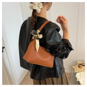 Brown lychee leather hobo bag with a decorative silk scarf worn over a black leather jacket