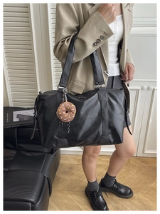 Chic black matte tote bag with donut plush charm shown on a stylish model in office attire