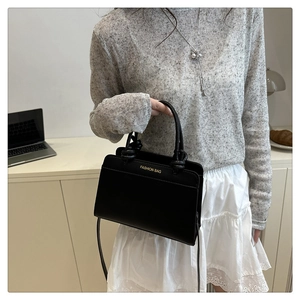 Detail of minimalist black handbag with gold Fashion Bag text and slim shoulder strap