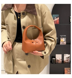 Detail of a brown leather hobo bag with dual zipper closure and a minimalist design