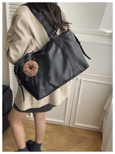 Détail d'un grand sac cabas en cuir noir avec un pendentif peluche en forme de donut