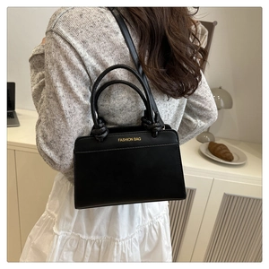 Detail of elegant black leather handbag with gold Fashion Bag print and slim strap