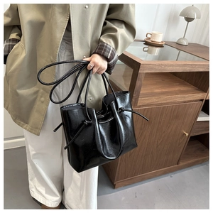 Dettaglio della borsa tote in vernice nera lucida con eleganti dettagli a coulisse annodata
