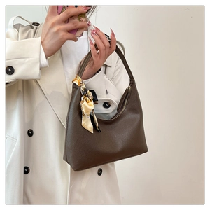 Detailed macro view of brown lychee grain leather handbag with silk scarf detail
