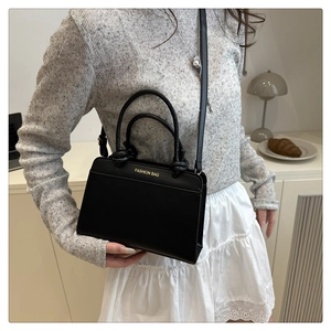 Detail of classic black leather tote bag with gold FASHION BAG text and dual handles
