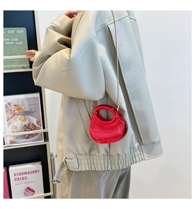 Detalle de mini bolso rojo metalizado plisado con cadena dorada y asa incorporada