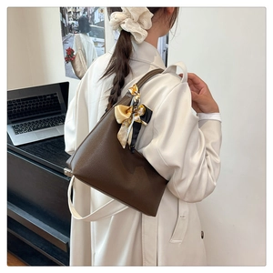 Detail of dark brown lychee leather texture and decorative silk scarf on the shoulder bag