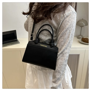 Detail of black leather handbag with gold Fashion Bag lettering and adjustable strap