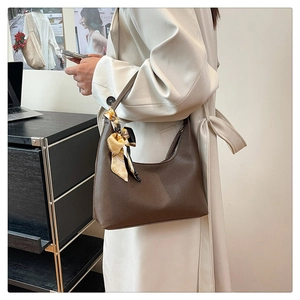 Detail of dark brown lychee leather hobo bag with a silk scarf tied on the handle