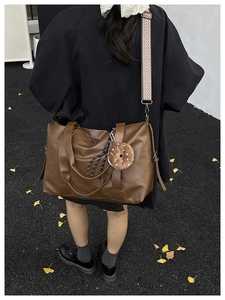 Detail of dark brown tote bag with patterned strap on ginkgo leaf autumn background