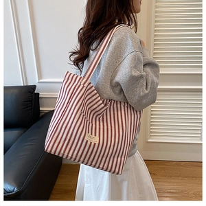 Detail view of large red and white striped canvas tote bag worn over the shoulder